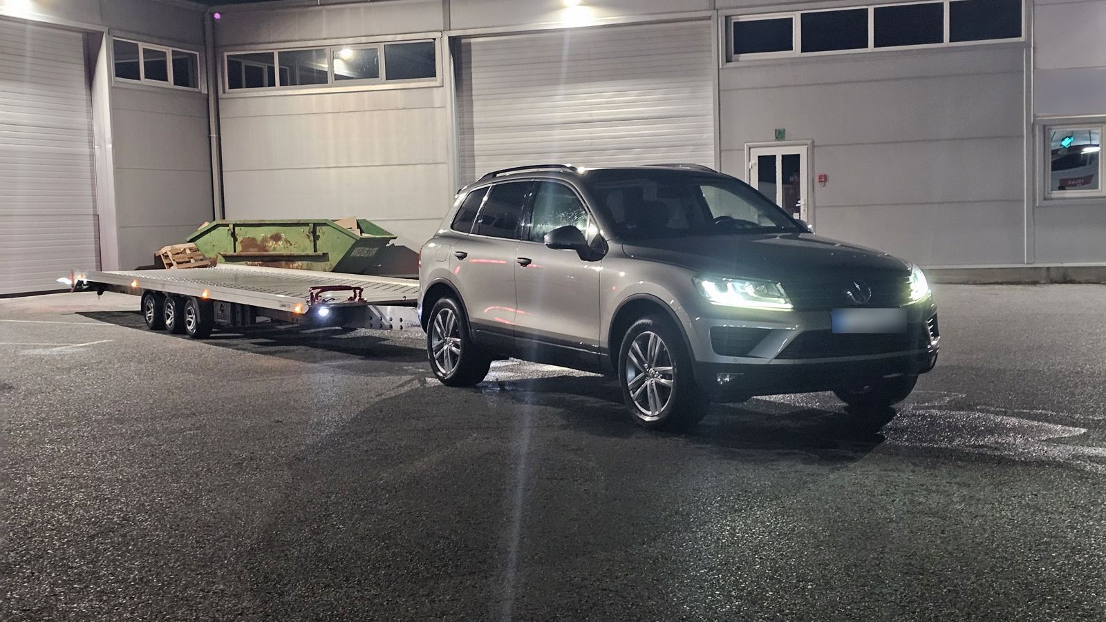VW Touareg mit Autoanhänger bei Nacht